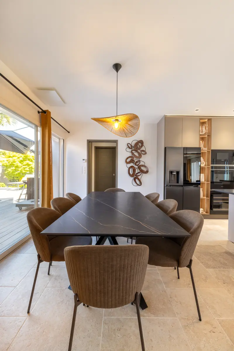 Le coin repas, table noire et suspension en rotin
