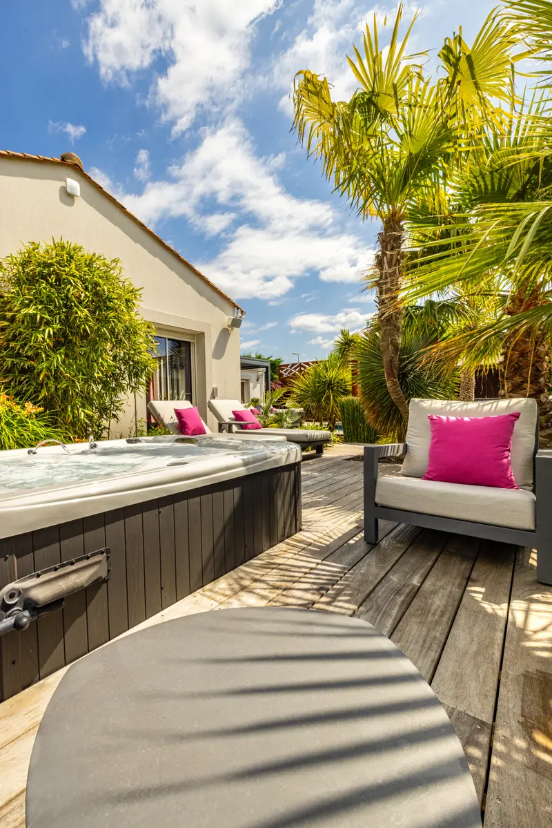 Le jacuzzi sur la terrasse bois, devant la maison