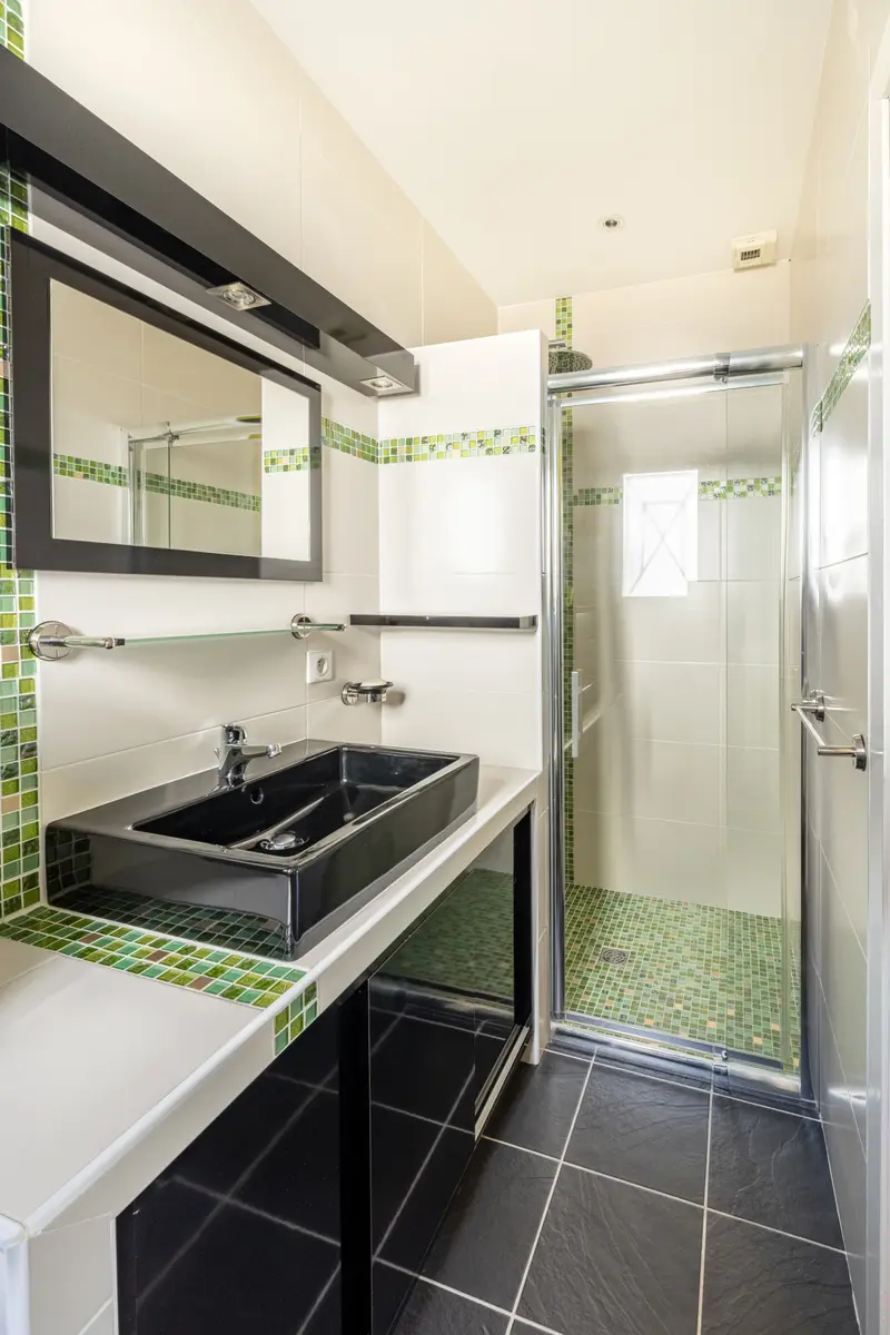 Salle d’eau verte, vasque noire et douche à l’italienne